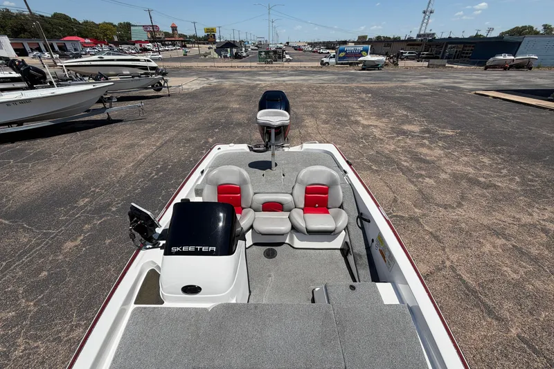 Slide: The Image of 2008 Skeeter SX190 boat with red and gray seating, parked in a marina lot. - 11