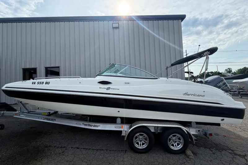 The Image of 2011 Hurricane SunDeck 237 OB boat on trailer, parked outside a building. - 0