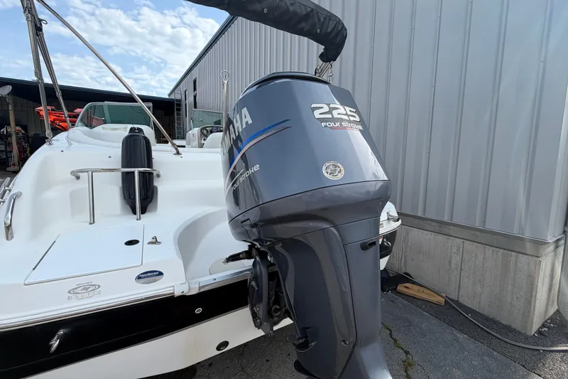 Slide: The Image of 2011 Hurricane SunDeck 237 OB with Yamaha 225 outboard motor, docked near a metal building. - 5