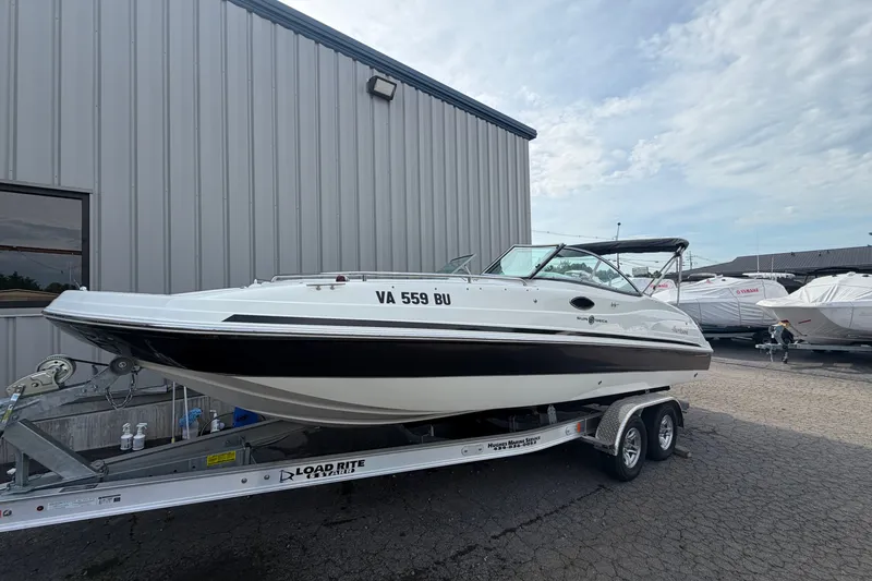 Slide: The Image of 2011 Hurricane SunDeck 237 OB boat on trailer, parked outside a metal building. - 1