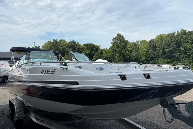 Slide: The Image of 2011 Hurricane SunDeck 237 OB boat on trailer, parked outdoors with trees in background. - 2