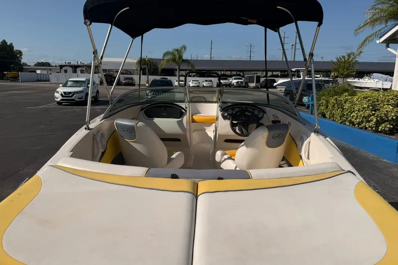 Slide: The Image of 2006 Sea Ray 185 Sport boat interior with yellow and white seating, parked outdoors. - 6