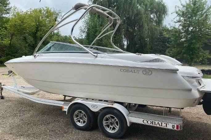 Slide: The Image of 2007 Cobalt 240 boat on trailer, parked outdoors with trees in background. - 3