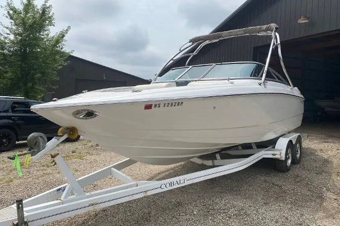 Slide: The Image of 2007 Cobalt 240 boat on trailer, parked outdoors near a building. - 2