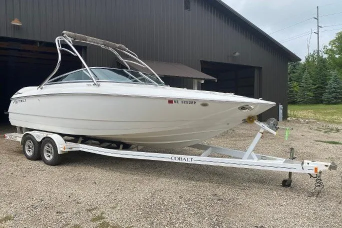 The Image of 2007 Cobalt 240 boat on trailer outside a large garage. - 0