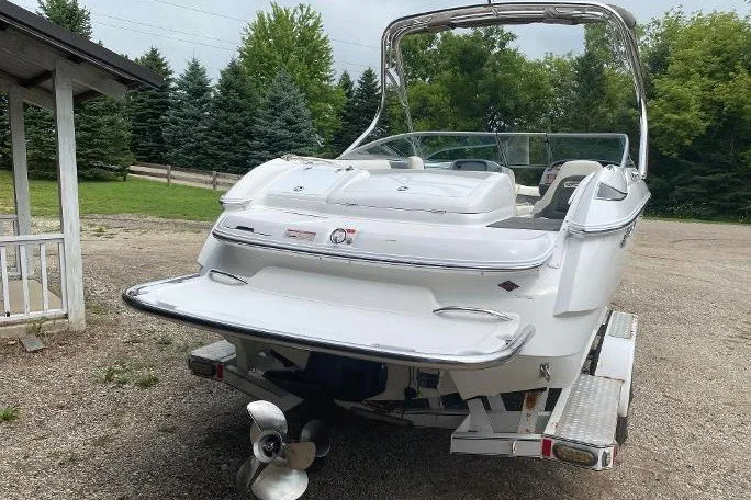 Slide: The Image of 2007 Cobalt 240 boat on trailer, parked outdoors with trees in the background. - 4