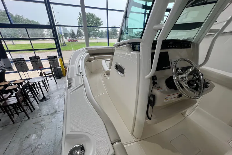 Slide: The Image of 2019 Boston Whaler 280 Outrage boat interior with steering wheel and seating in showroom. - 16