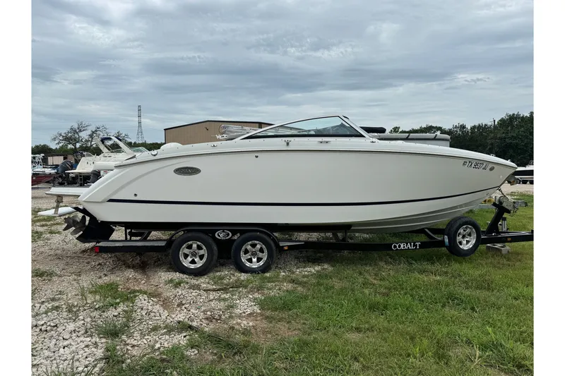 The Image of 2013 Cobalt R5 boat on trailer, parked outdoors under cloudy sky. - 1