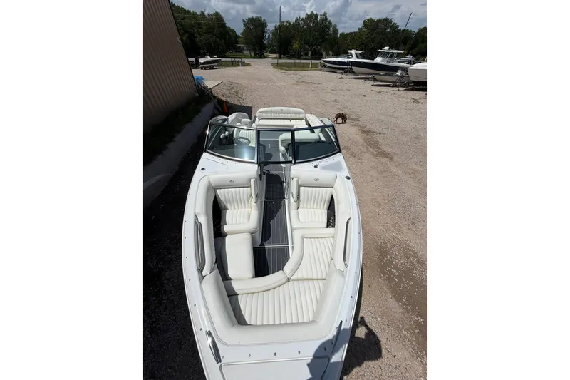 Slide: The Image of 2013 Cobalt R5 boat with white interior, parked on gravel near other boats. - 2