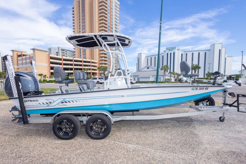 Slide: The Image of 2024 Xpress H22 Bay boat on trailer, urban backdrop, clear sky. - 9