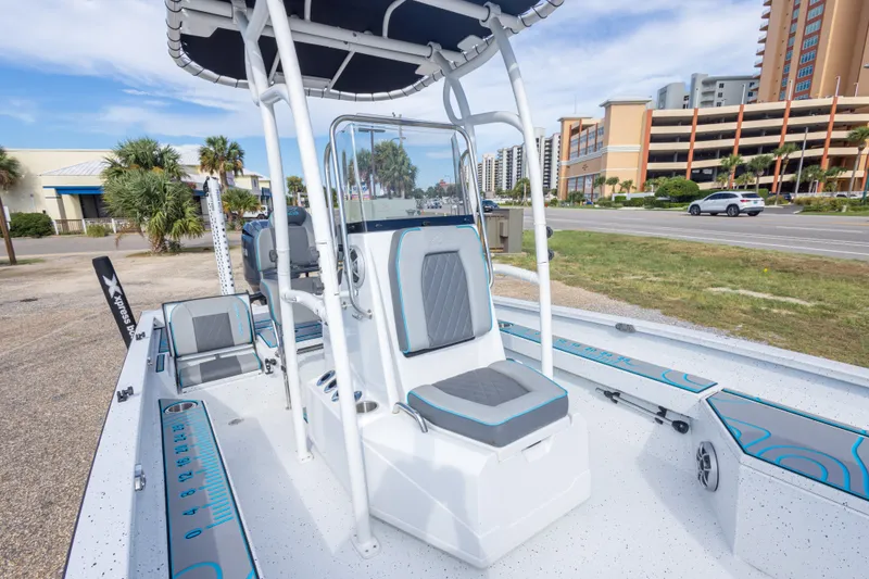 Slide: The Image of 2024 Xpress H22 Bay boat with modern seating and console, parked near a coastal road. - 36