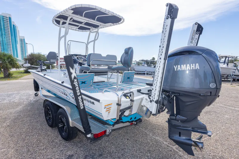 Slide: The Image of 2024 Xpress H22 Bay boat with Yamaha engine, parked on a trailer near waterfront buildings. - 17
