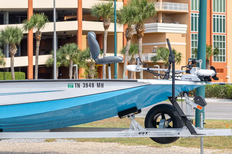 Slide: The Image of 2024 Xpress H22 Bay boat on trailer, parked near palm trees and buildings. - 11