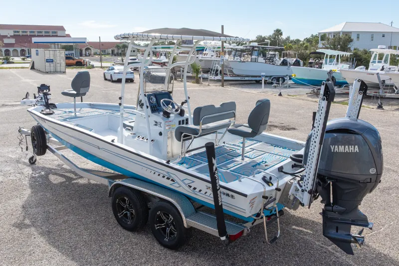 Slide: The Image of 2024 Xpress H22 Bay boat with Yamaha engine, parked on a trailer in a marina. - 55