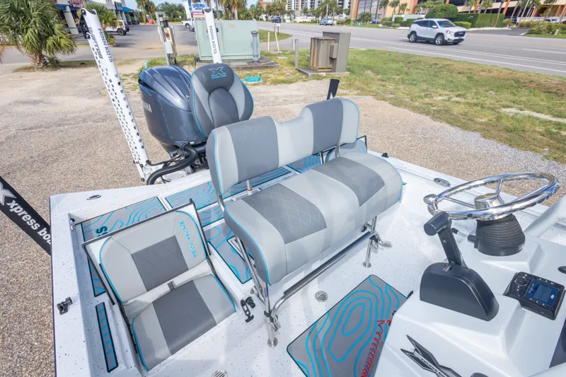 Slide: The Image of 2024 Xpress H22 Bay boat interior with seating and steering wheel, parked outdoors. - 41
