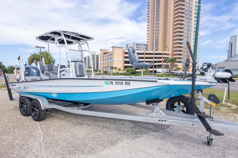 Slide: The Image of 2024 Xpress H22 Bay boat on trailer, parked near tall buildings. - 12