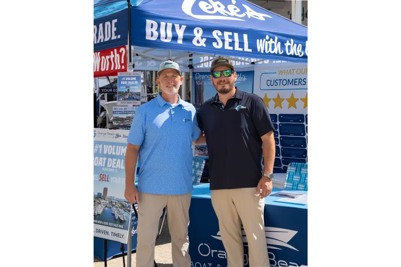 Slide: The Image of Two men at a boat dealership event under a branded tent. - 8