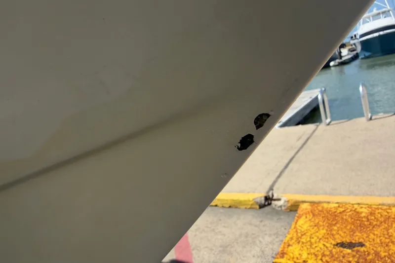 Slide: The Image of 2006 World Cat 270 TE boat hull with visible damage near marina dock. - 52