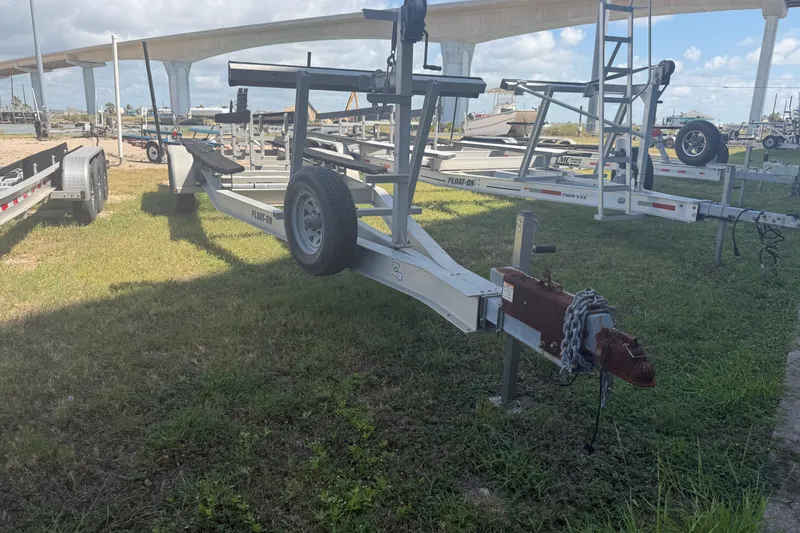 Slide: The Image of Boat trailer parked on grass, under a bridge, for a 2006 World Cat 270 TE. - 56