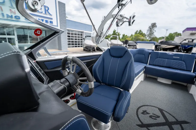 Slide: The Image of 2021 MasterCraft X24 boat interior with blue seating and steering wheel, at a dealership. - 40
