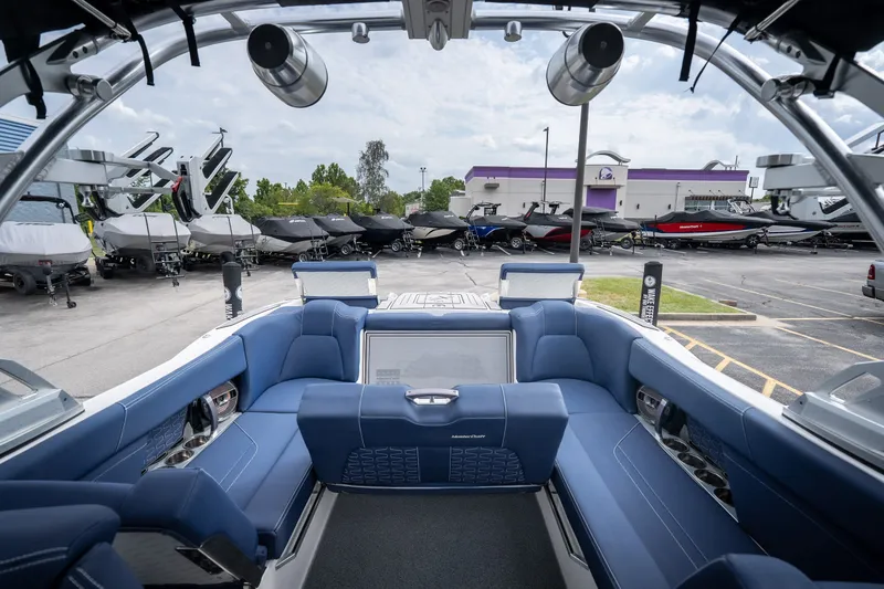 Slide: The Image of Interior view of a 2021 MasterCraft X24 boat with blue seating, parked in a dealership lot. - 47