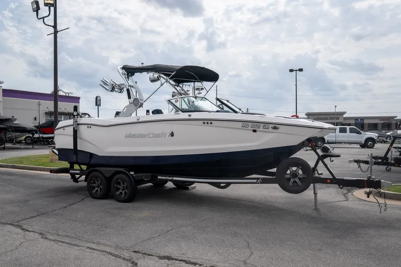 Slide: The Image of 2021 MasterCraft X24 boat on trailer in parking lot, overcast sky. - 9