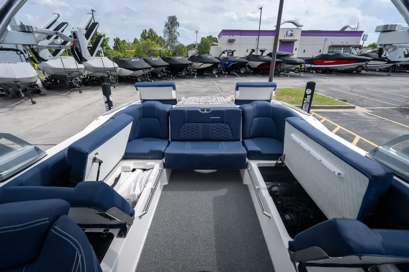 Slide: The Image of 2021 MasterCraft X24 boat interior with blue seating and storage compartments, parked in a dealership lot. - 46