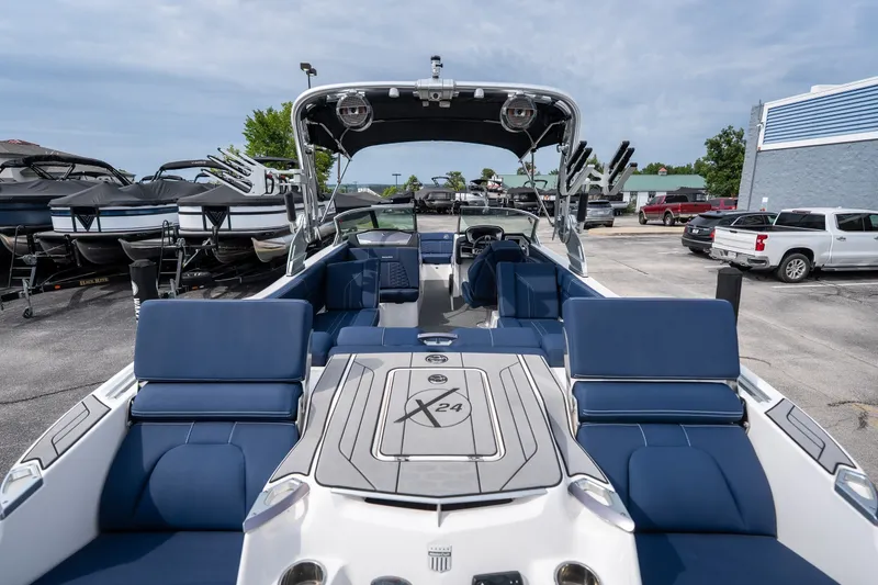Slide: The Image of 2021 MasterCraft X24 boat with blue seating, parked in a marina. - 22