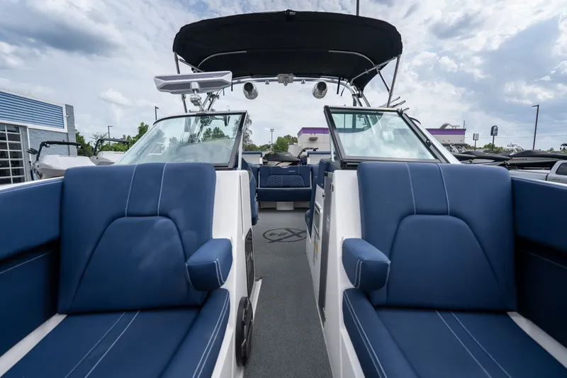 Slide: The Image of 2021 MasterCraft X24 boat interior with blue seating and canopy under cloudy sky. - 37