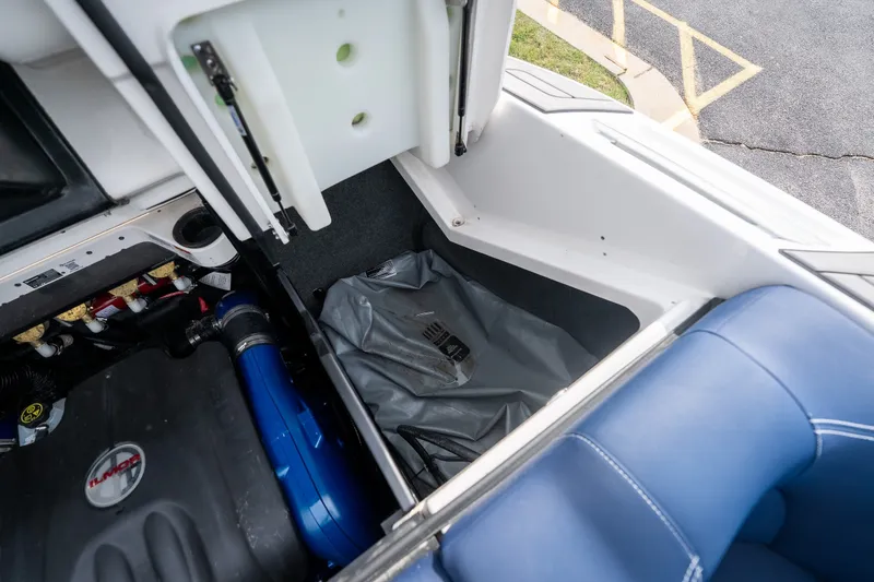 Slide: The Image of 2021 MasterCraft X24 boat storage compartment with engine and blue upholstery. - 53