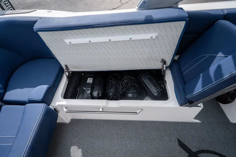 Slide: The Image of 2021 MasterCraft X24 boat storage compartment with blue seating and open lid. - 45