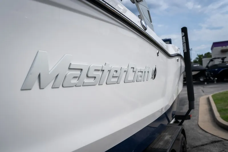 Slide: The Image of 2021 MasterCraft X24 boat side view with logo, parked outdoors. - 17