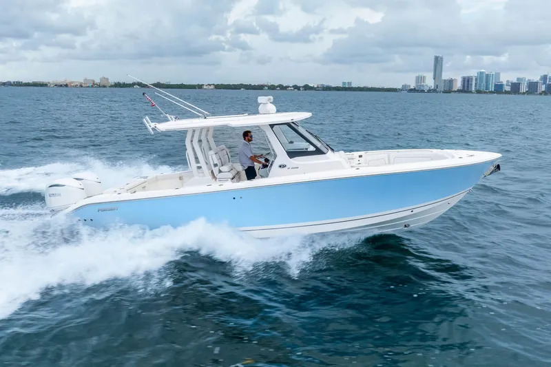 Slide: The Image of 2025 Pursuit S 328 Sport boat cruising on open water with city skyline backdrop. - 4