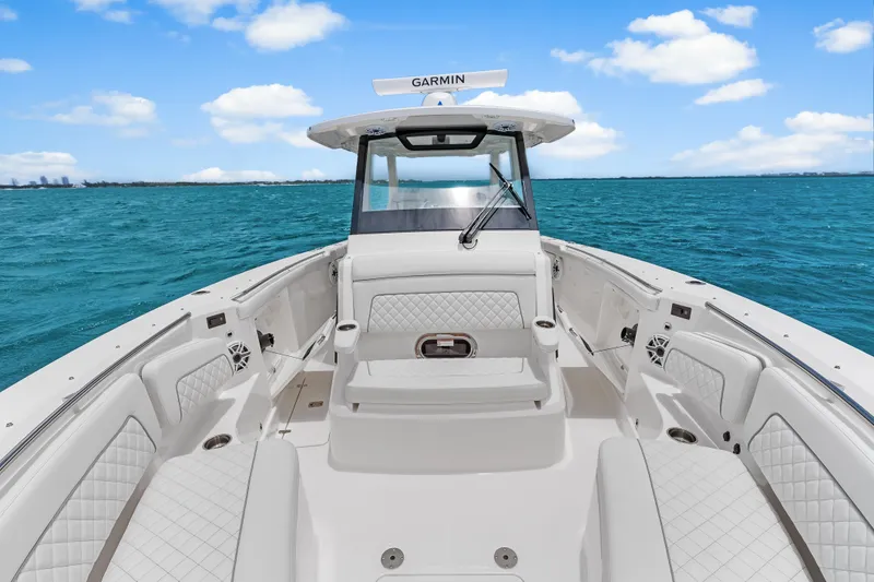 Slide: The Image of 2025 Pursuit S 328 Sport boat interior with white seating, on blue ocean water. - 11