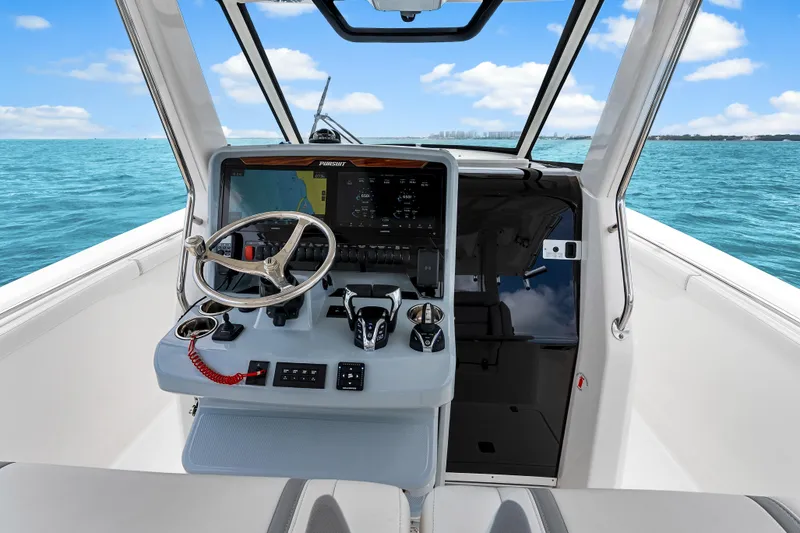 Slide: The Image of 2025 Pursuit S 328 Sport boat helm with modern controls, steering wheel, and ocean view. - 24