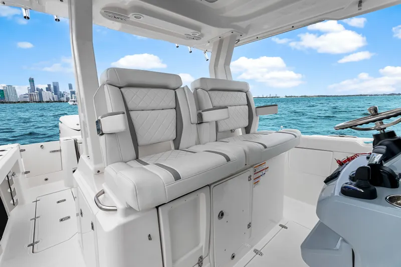 Slide: The Image of 2025 Pursuit S 328 Sport boat interior with luxurious seating, ocean view, and city skyline. - 21