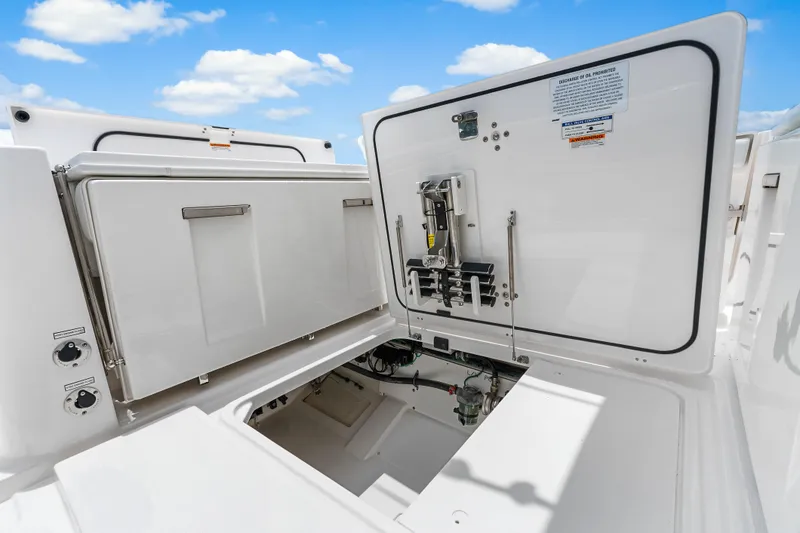 Slide: The Image of 2025 Pursuit S 328 Sport boat storage compartment with open hatches under a blue sky. - 34