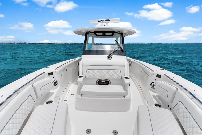 Slide: The Image of 2025 Pursuit S 328 Sport boat interior with white seating, on blue ocean under clear sky. - 12