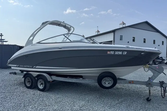 Slide: The Image of 2015 Yamaha Boats 242 Limited S on trailer, parked on gravel near a building. - 1