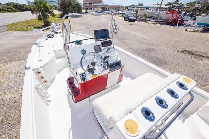 Slide: The Image of 2003 Triton 220 LTS boat interior with steering console and seating, docked outdoors. - 27