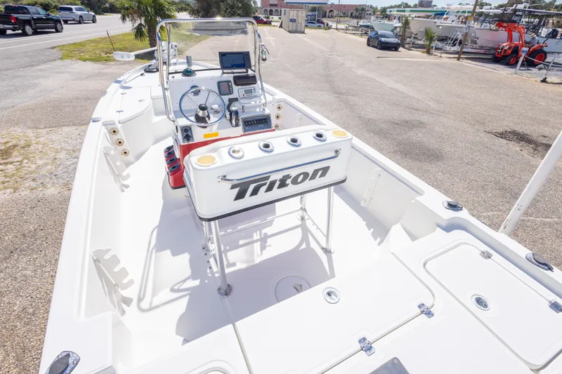 Slide: The Image of 2003 Triton 220 LTS boat interior with steering console and equipment, parked outdoors. - 23