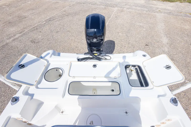Slide: The Image of 2003 Triton 220 LTS boat deck with open storage compartments and outboard motor. - 46