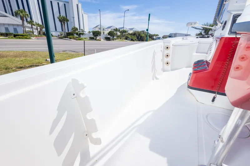 Slide: The Image of 2003 Triton 220 LTS boat interior with red console, white deck, and urban background. - 43