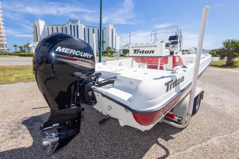 Slide: The Image of 2003 Triton 220 LTS boat with Mercury engine on a trailer, parked outdoors. - 13