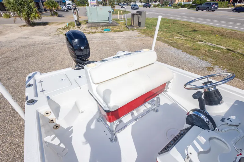Slide: The Image of 2003 Triton 220 LTS boat interior with steering wheel and seating, parked near a road. - 40
