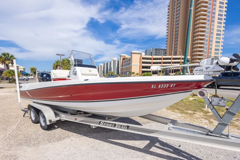 Slide: The Image of 2003 Triton 220 LTS boat on trailer, parked near tall buildings under a blue sky. - 12