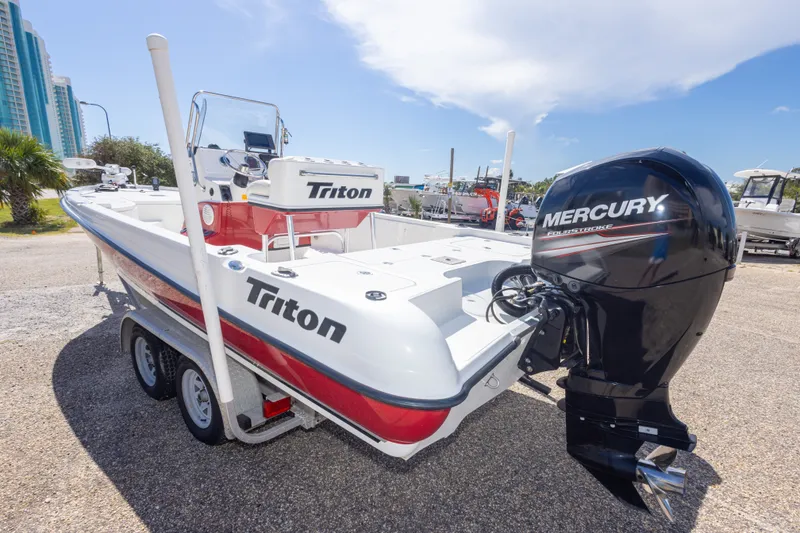 Slide: The Image of 2003 Triton 220 LTS boat with Mercury engine, parked on a trailer in a sunny marina. - 16