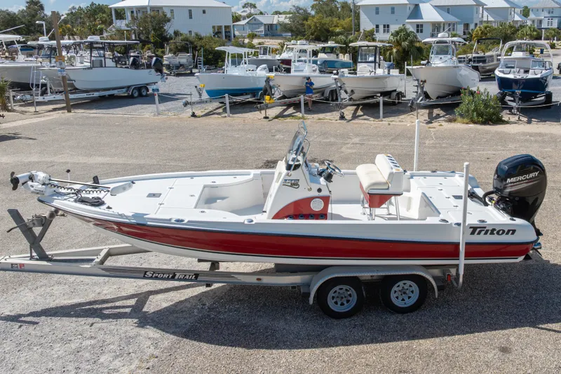 Slide: The Image of 2003 Triton 220 LTS boat on trailer, parked in marina with other boats. - 3