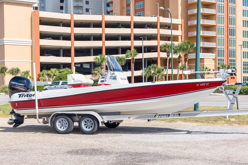 The Image of 2003 Triton 220 LTS boat on trailer, parked near modern buildings. - 0