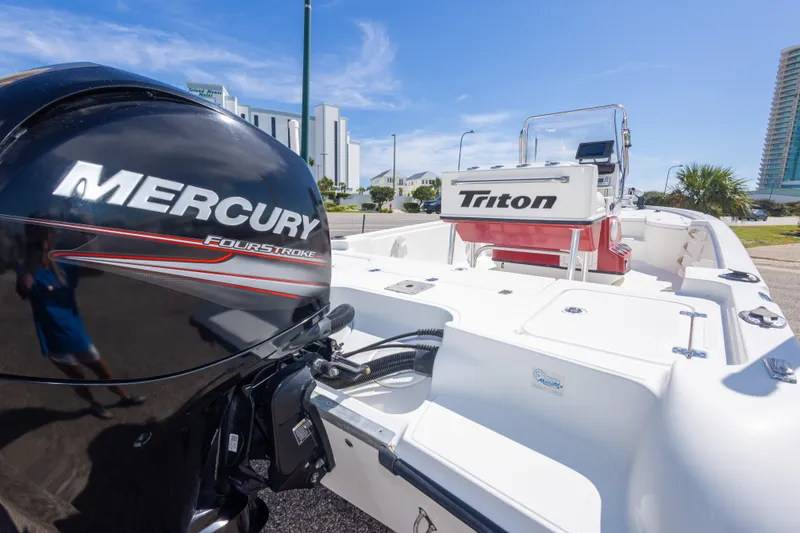 Slide: The Image of 2003 Triton 220 LTS boat with Mercury FourStroke engine, parked outdoors on a sunny day. - 21